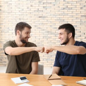 Two happy young men giving fist bump