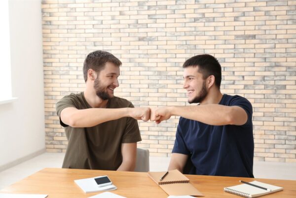 Two happy young men giving fist bump